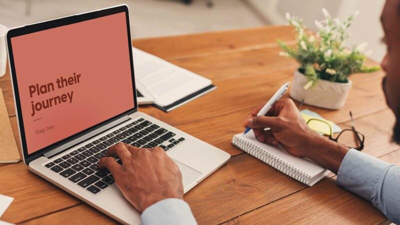A man on a laptop takes notes during a "Plan their journey" presentation.