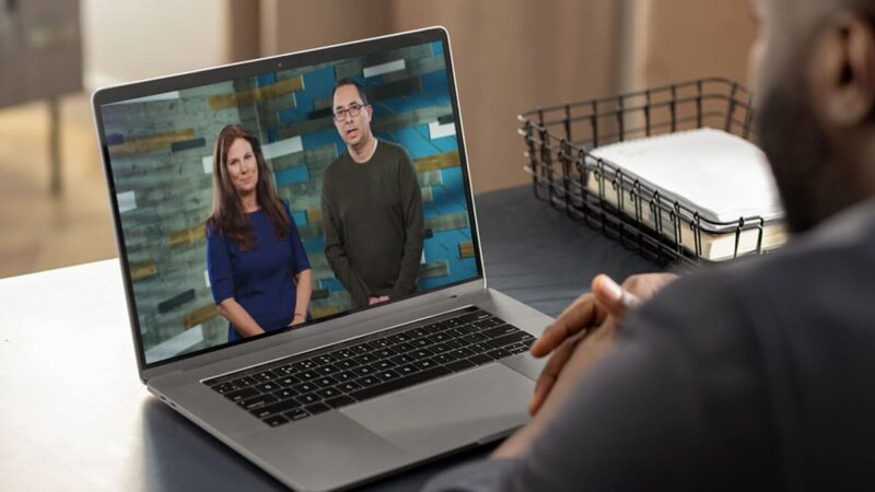 Nancy Duarte and another presenter appear on a laptop screen while a person watches.