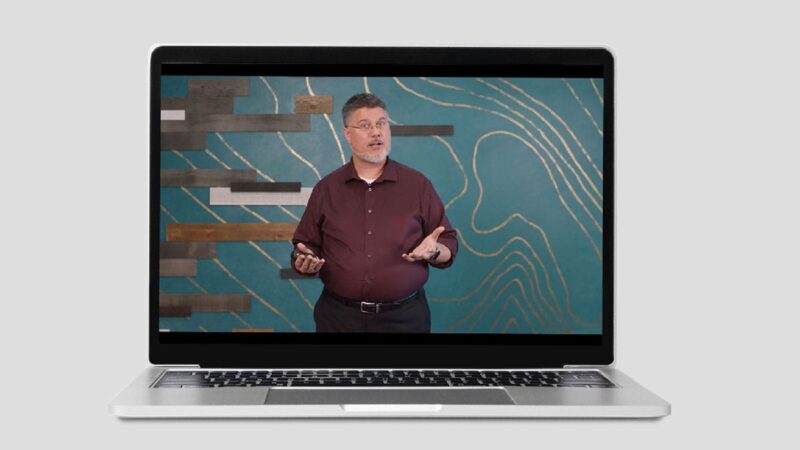 A laptop with a man leading a presentation on the screen.