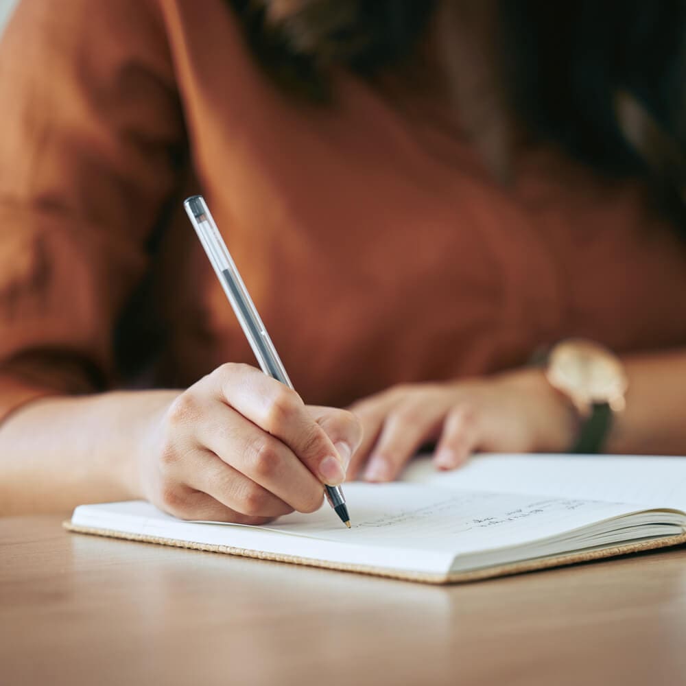 A person writes a note in a notebook.