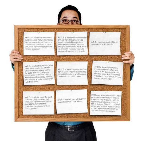 Man holding up a corkboard with notes on it