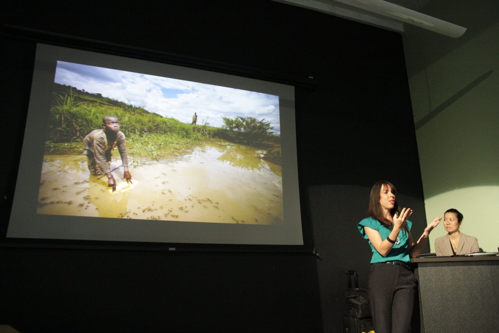 Giving a presentation with an image of a boy sifting through dirty water