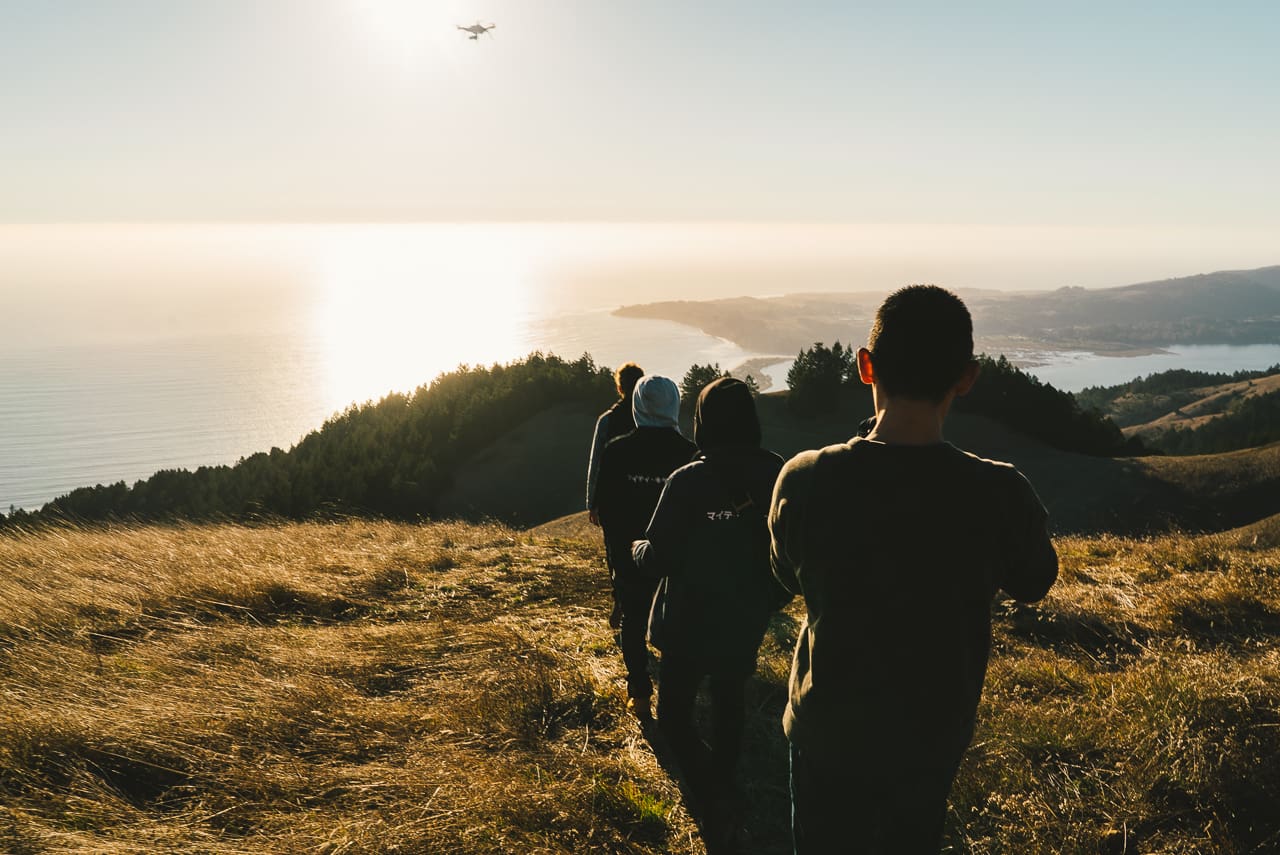 Photographers "Mighty Killers" explore grassland with body of ocean in front of them