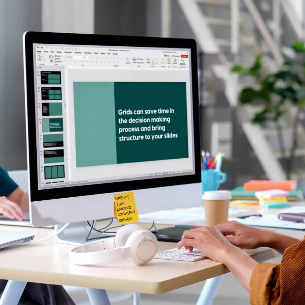 A person sits at a computer while editing presentation slides.