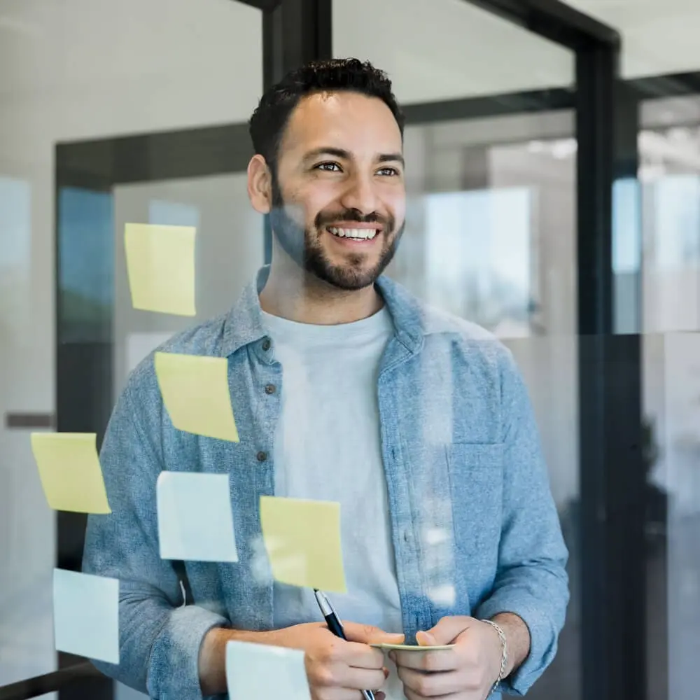 A man looking through a window with sticky notes on it.