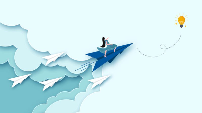 A person riding a paper airplane through open sky towards an illuminated light bulb. They’re being trailed by four other paper airplanes all headed in the same direction. This image symbolizes the 5 communication shifts that separate good and great leaders.