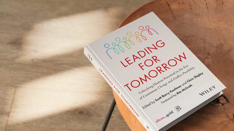 Hardcover copy of Leading for Tomorrow: Unlocking Human Potential in the Era of Continuous Change and Endless Possibility sitting on a table in sunlight.